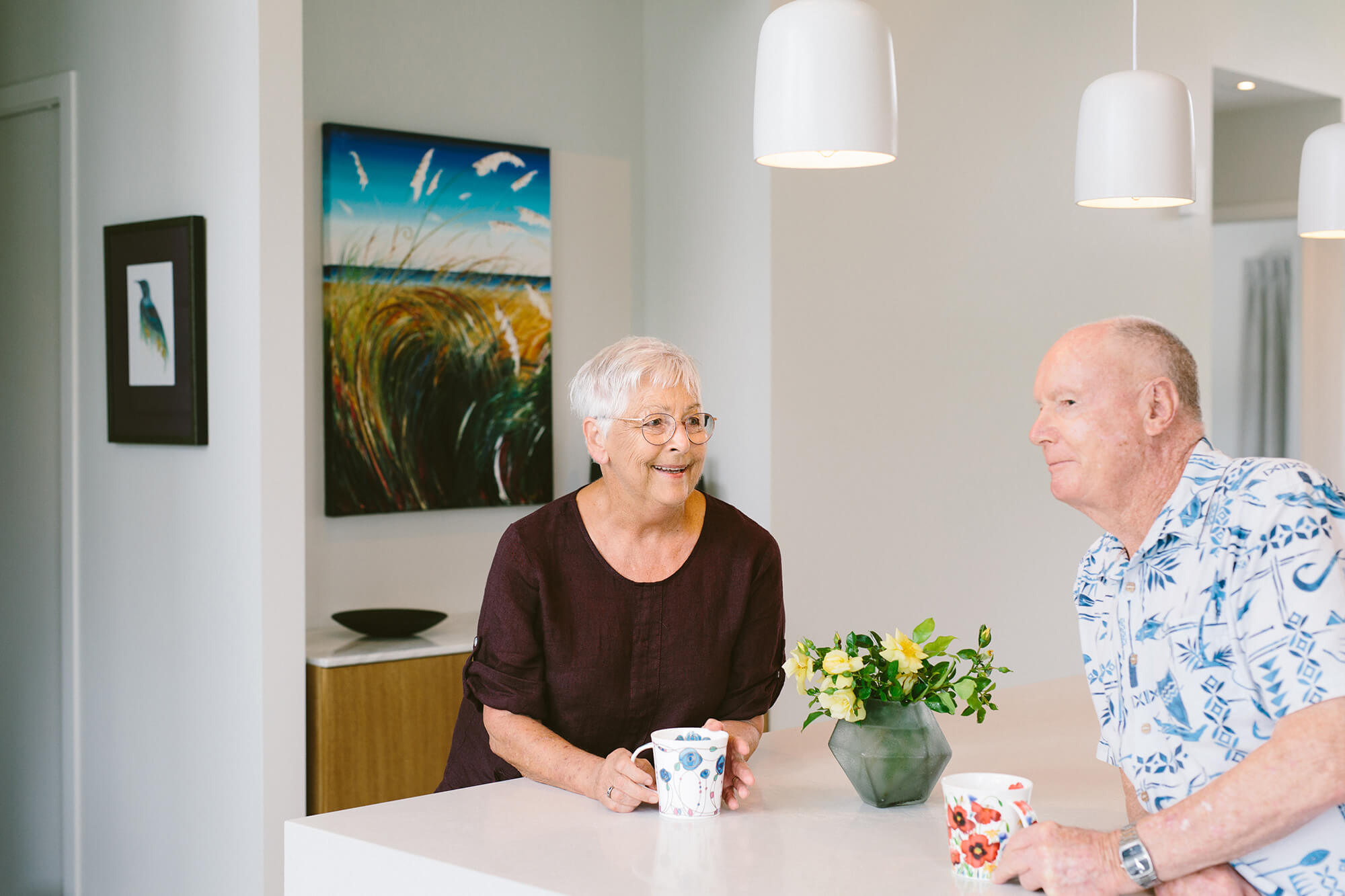 Retired couple enjoying a cup of tea in the kitchen of their villa home.