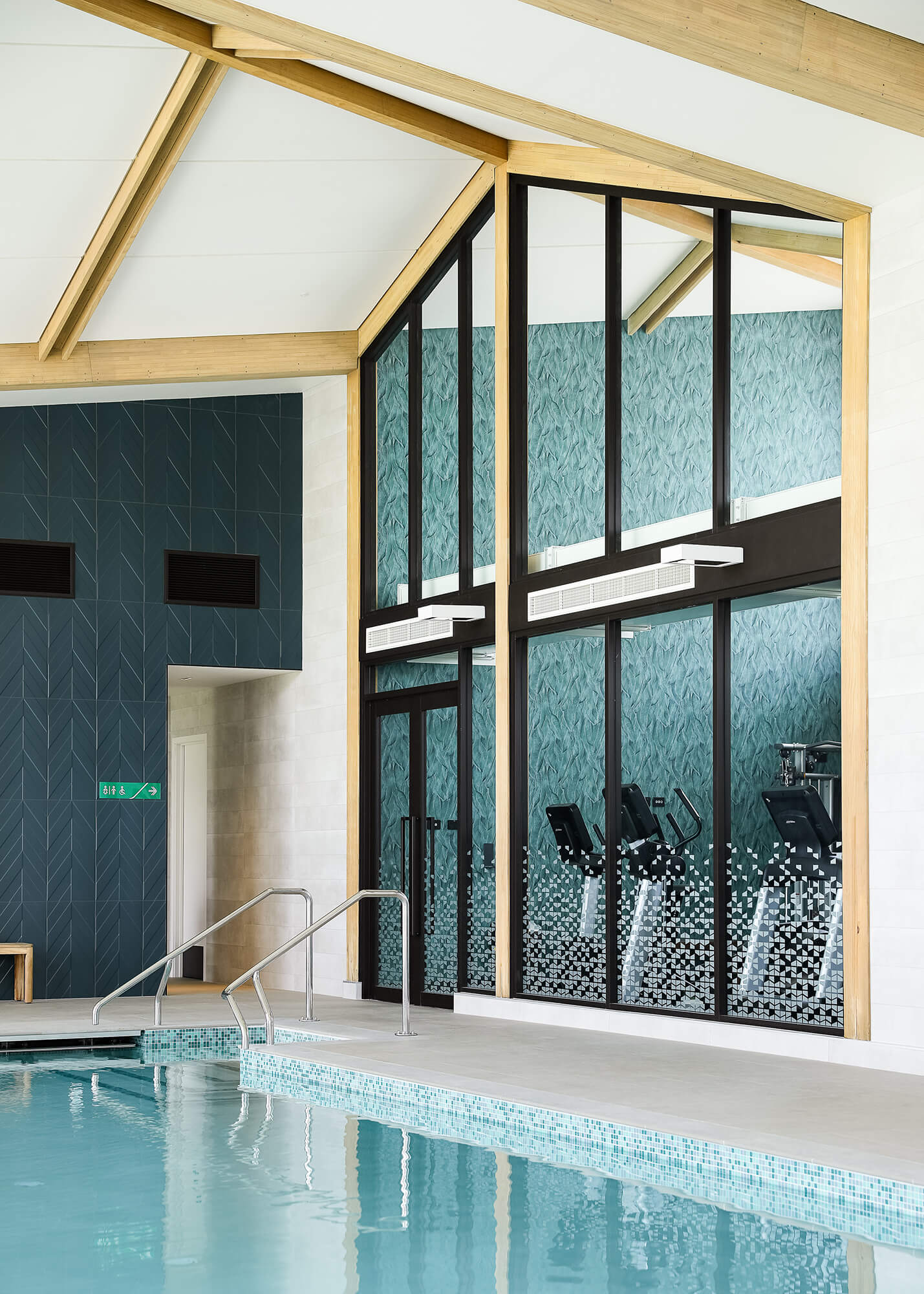 Gym room overlooks an indoor pool through large windows.