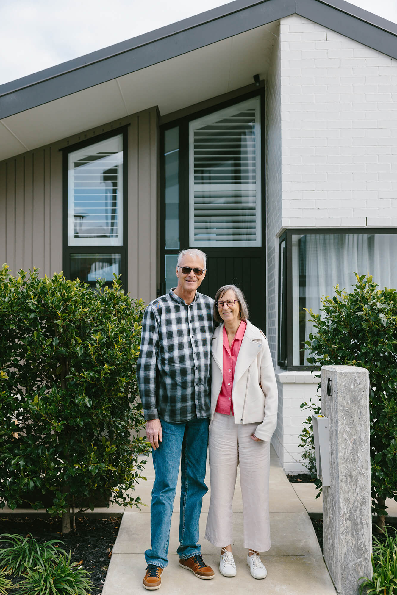 Couple stand together outside of their villa home.