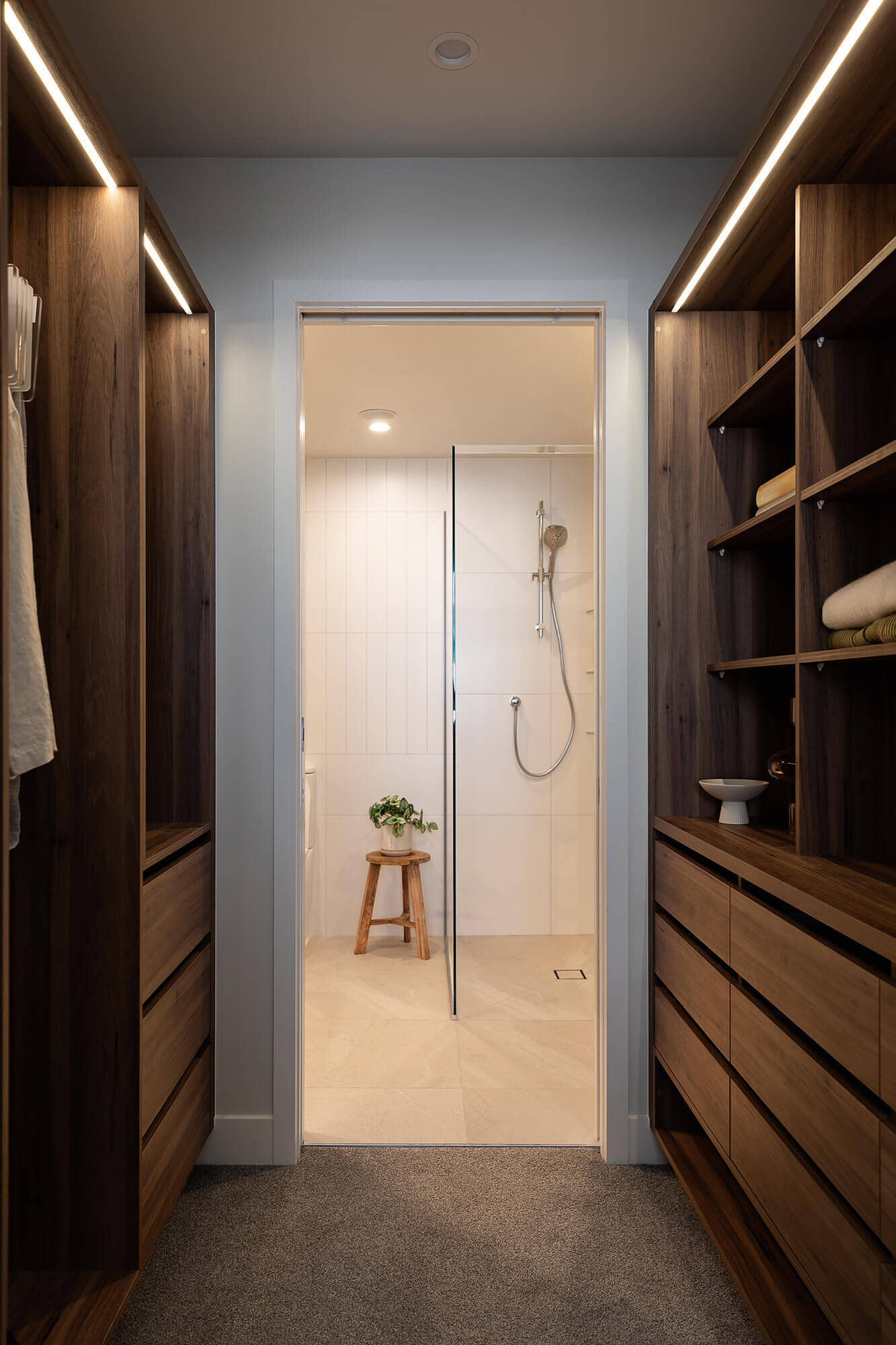 Master ensuite is accessed through the walk-in wardrobe, which is fitted with wooden shelving and strip lights.