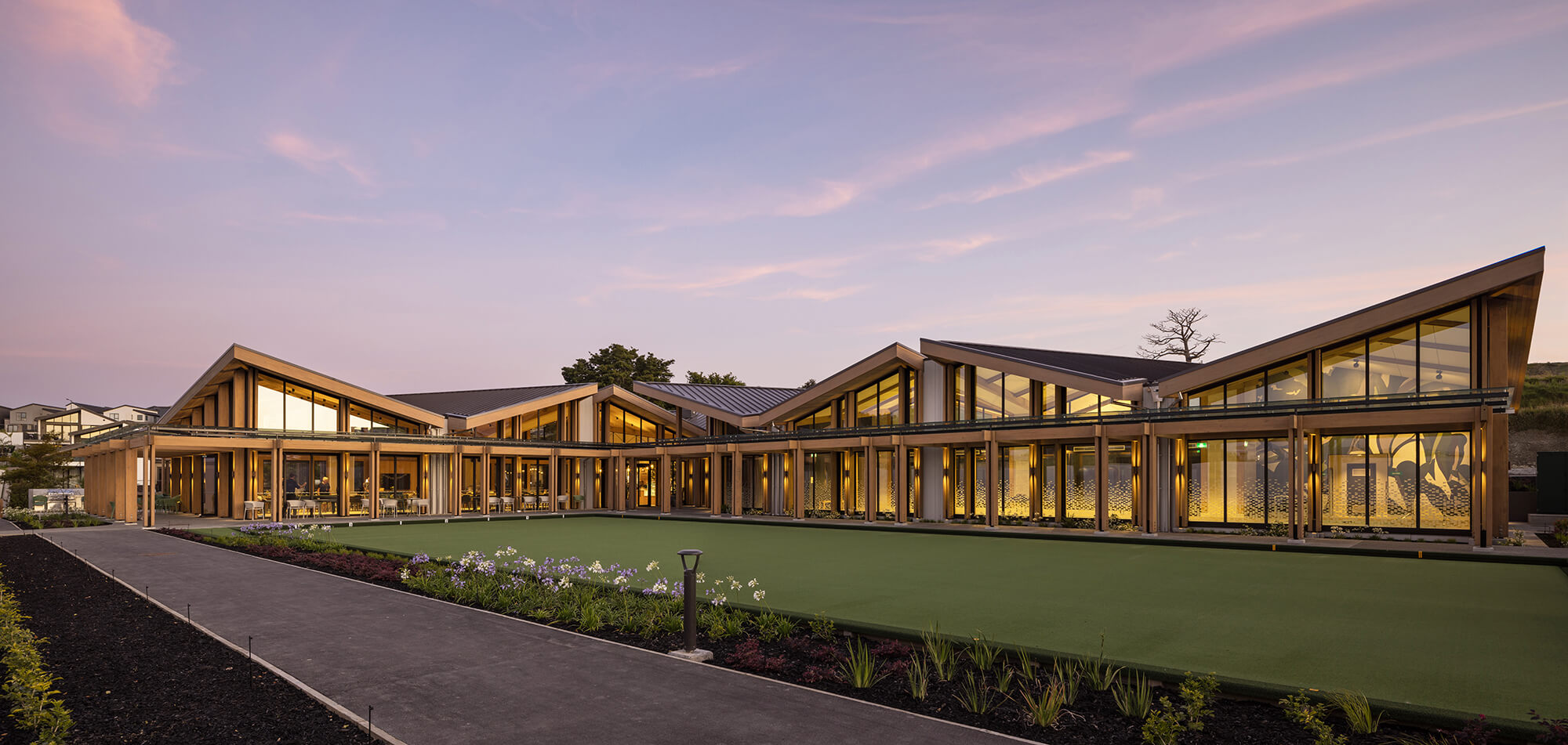 The exterior of the The Club House lit up by the inside lights as the sun sets.