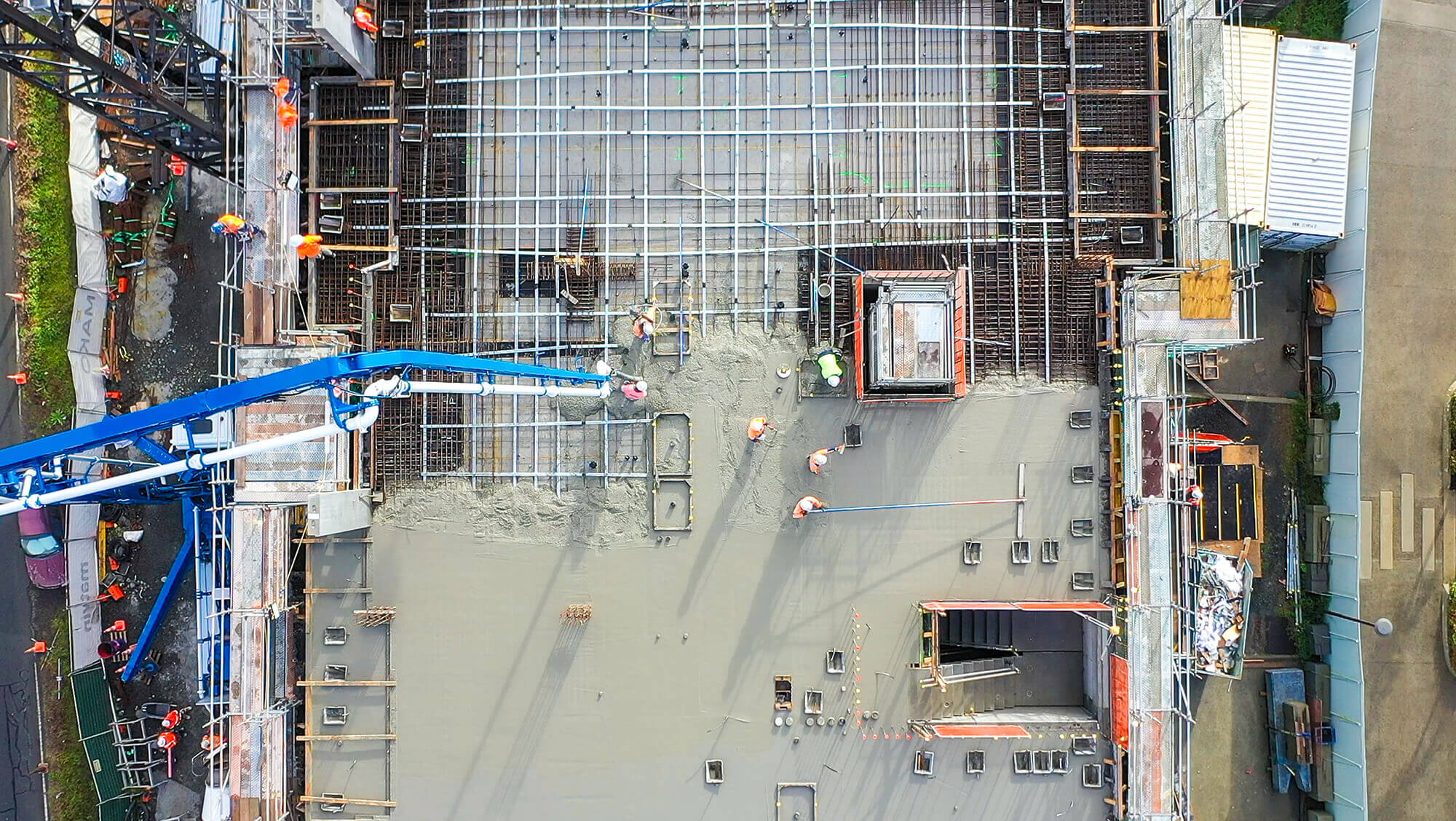 Birds eye view of an apartment building construction site where concrete is part way through being poured.