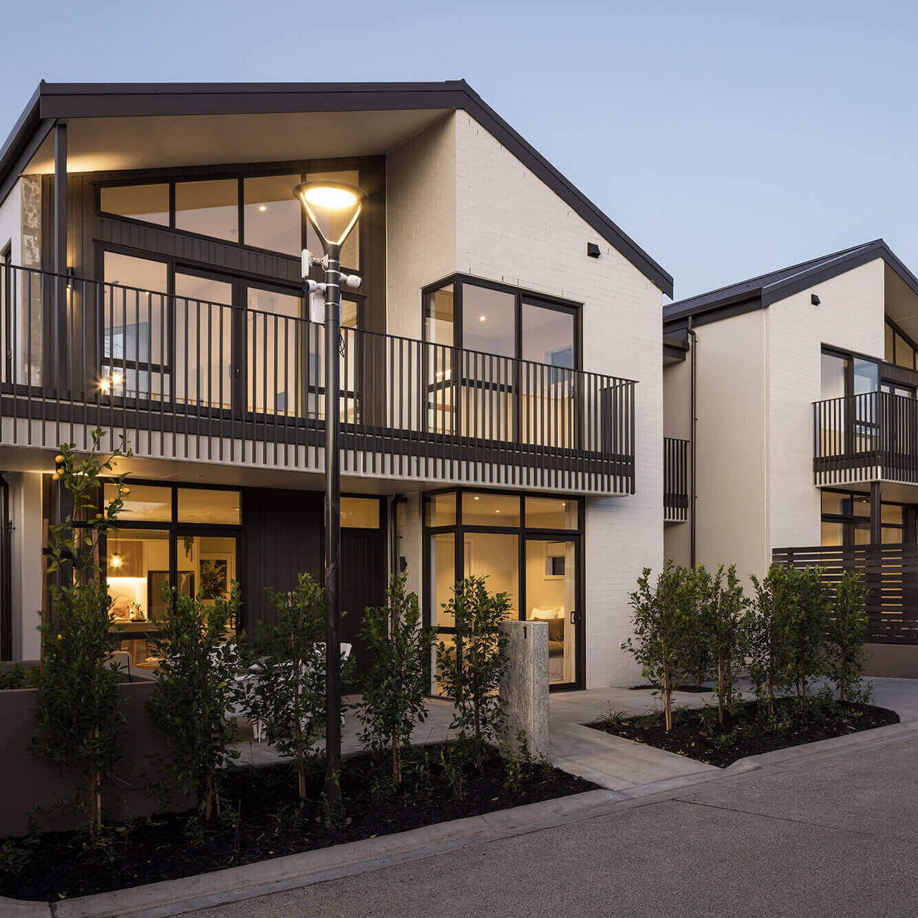 Exterior of a duplex villa at The Botanic Silverdale, lights on illuminate the interior.